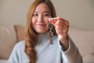 Jeune femme montrant des clés d'un bien immobilier en période de crise